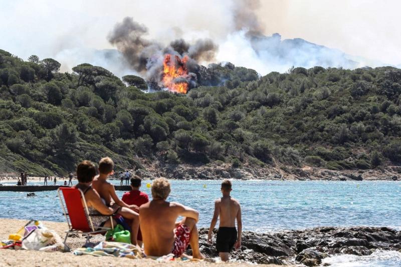 Des gens profitent de la plage en regardant un feu de forêt à La Croix-Valmer, près de Saint-Tropez, le 25 Juillet, 2017. Valery Hache/AFP
