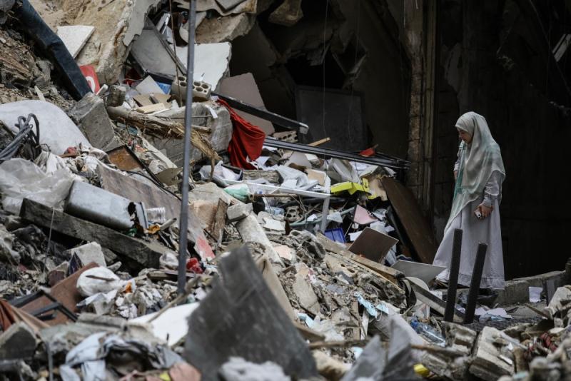 A woman standing amid the debris of a destroyed building